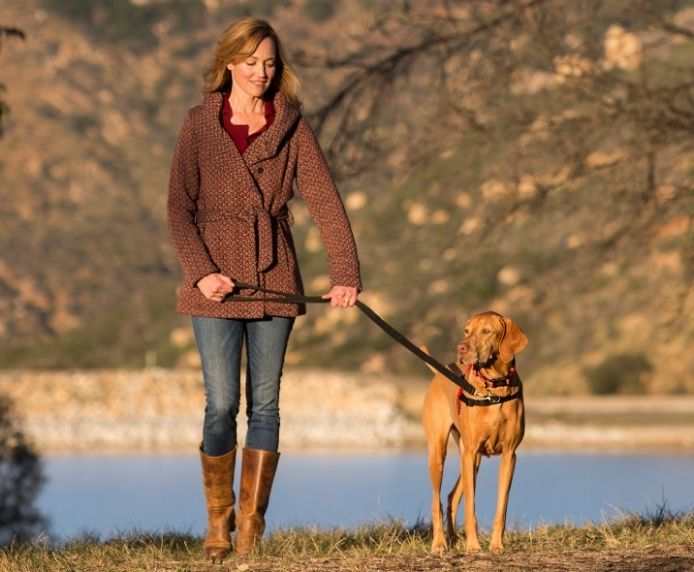 Woman walking dog with HALTI Front Control Harness near a lake.